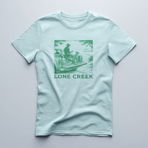 Woodcut-style truck and dog illustration in dark green on a Heather Mint graphic tee.