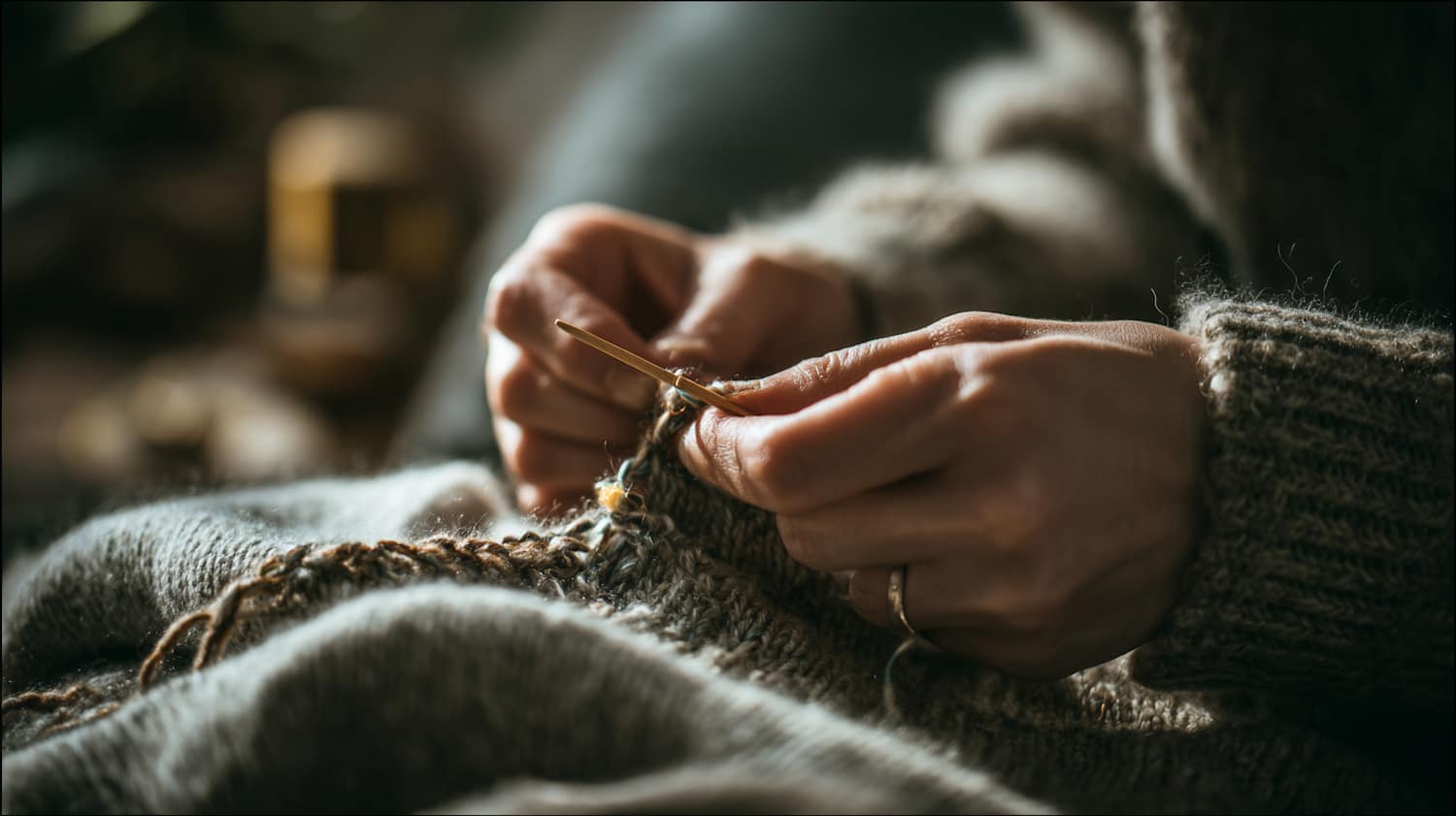 Hands stitching a small hole in a cotton shirt at a kitchen table with needle thread and sewing supplies