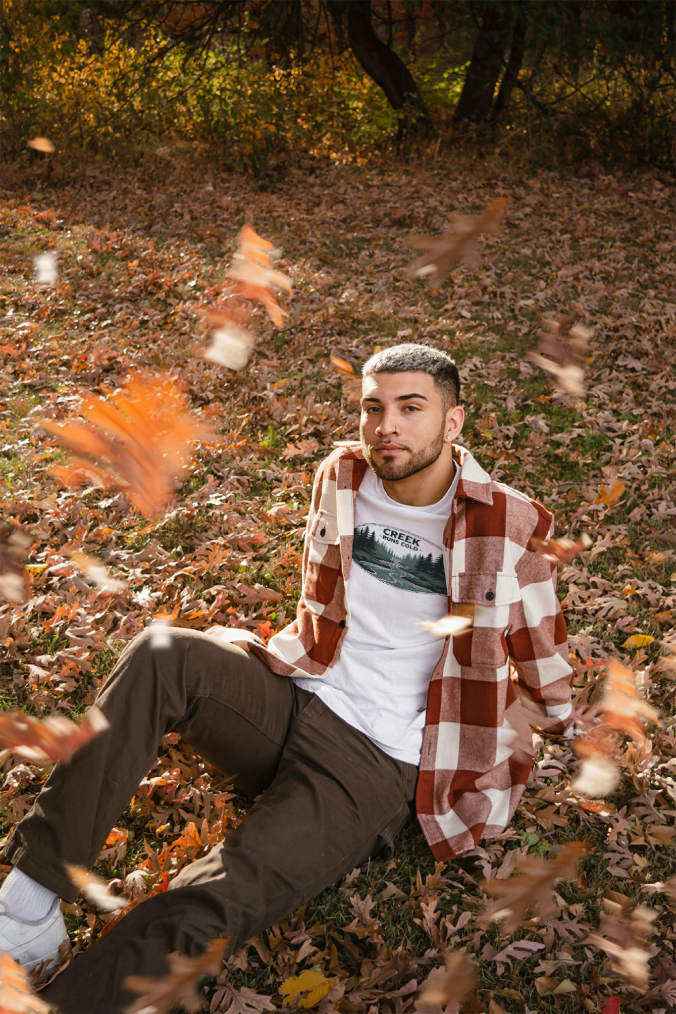 Man sitting on the ground with autumn leaves falling around him