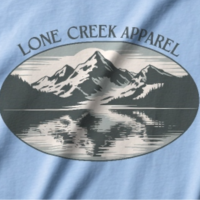 Light blue t-shirt with a mountain graphic and 'Lone Creek Apparel' text.