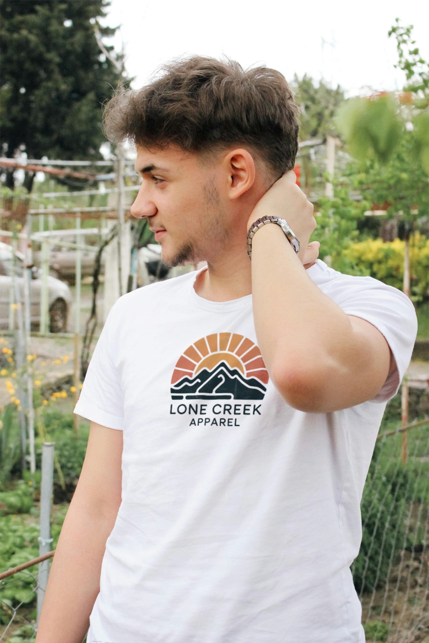 Person wearing a white t-shirt with Lone Creek Apparel logo outdoors