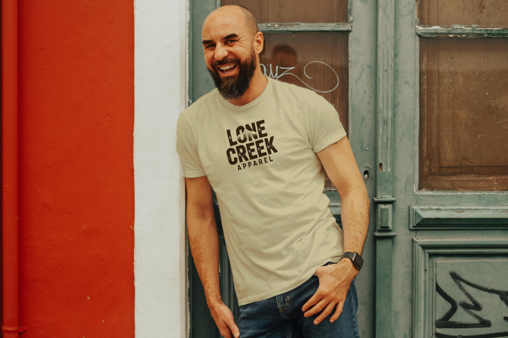 Man wearing a 'Lone Creek Apparel' t-shirt standing against a red and white wall.