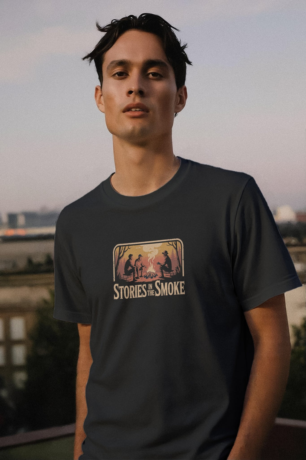 Man wearing a t-shirt with 'Stories in the Smoke' graphic design outdoors.