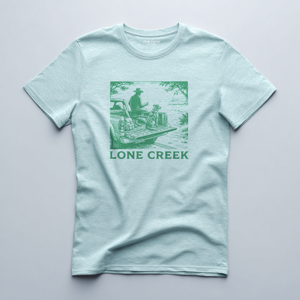 Woodcut-style truck and dog illustration in dark green on a Heather Mint graphic tee.