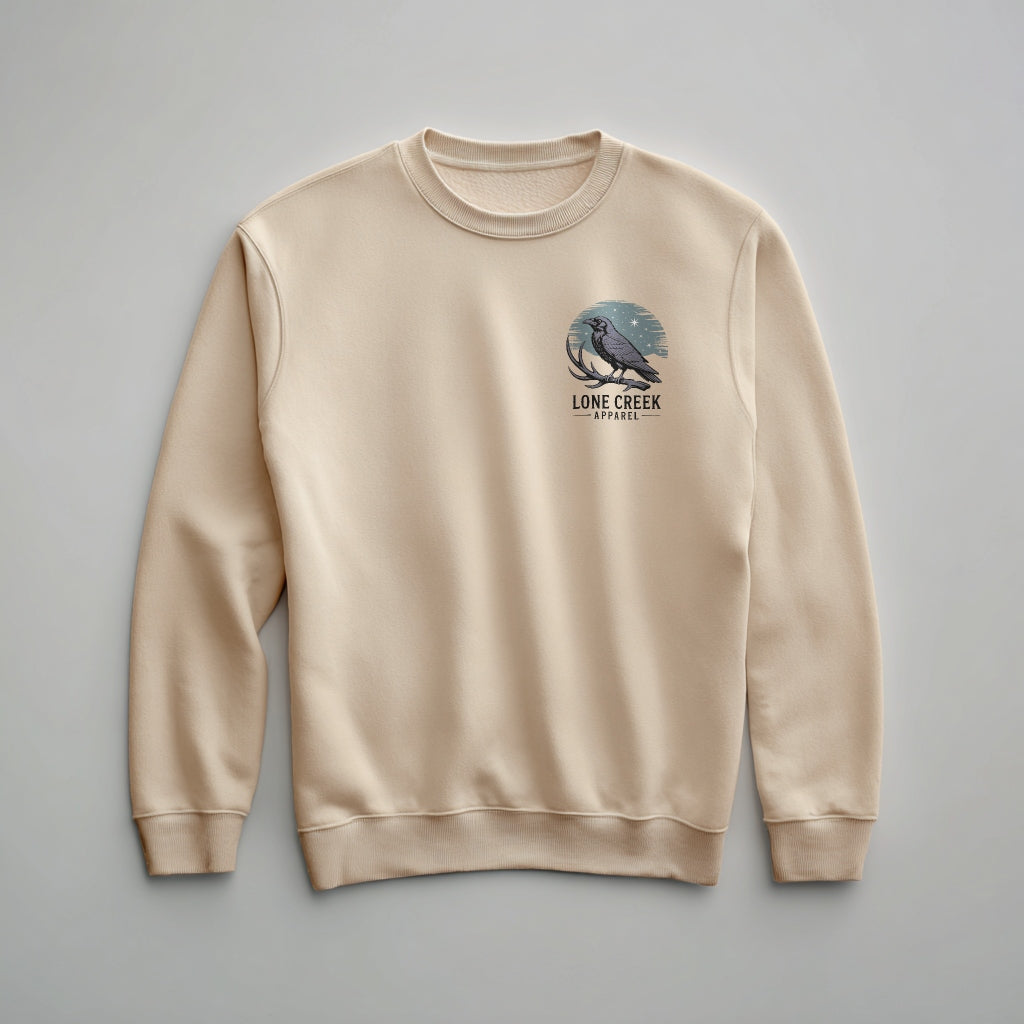 Dark fantasy woodcut illustration of a raven on an antler against a teal crescent moon on a Sand midweight fleece crewneck sweatshirt.